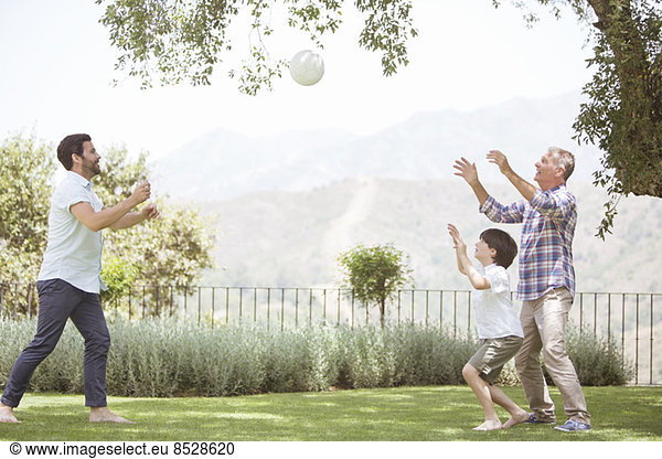 Multi-generation family playing volleyball in backyard