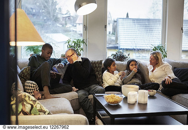 Multi-generation family sitting on sofa at home