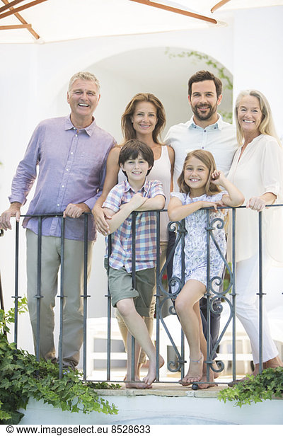 Multi-generation family smiling at balcony railing