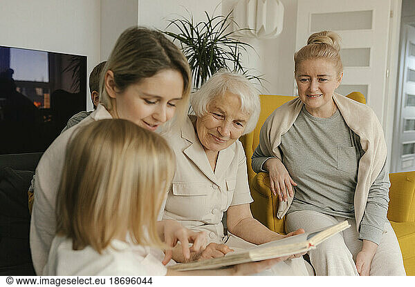 Multi-generation family with photo album sitting at home