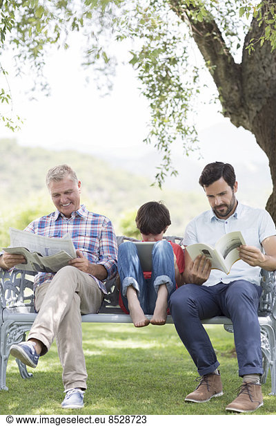 Multi-generation men reading on bench