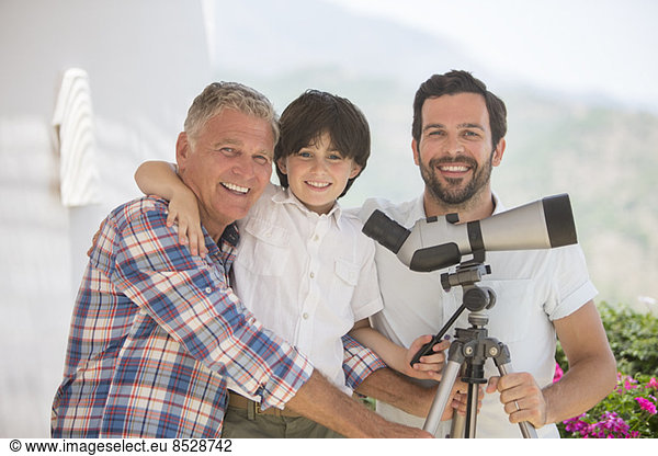 Multi-generation men using telescope outdoors