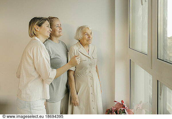 Multi-generation women looking out of window at home