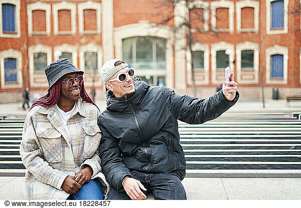 multiethnic couple using phone taking selfie  on the street