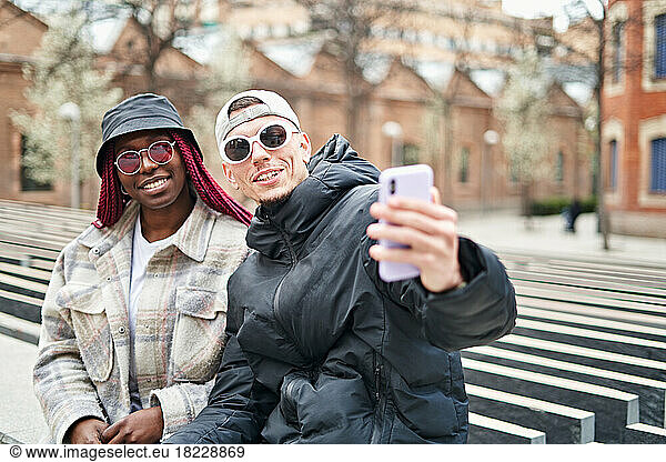 multiethnic couple using phone taking selfie  on the street
