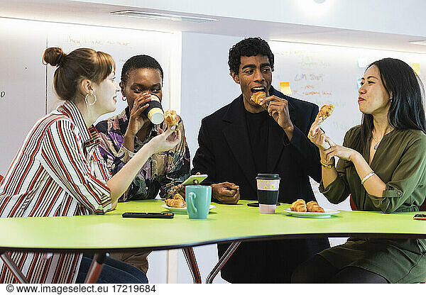 Multiethnische Geschäftsleute beim gemeinsamen Essen und Trinken im Büro