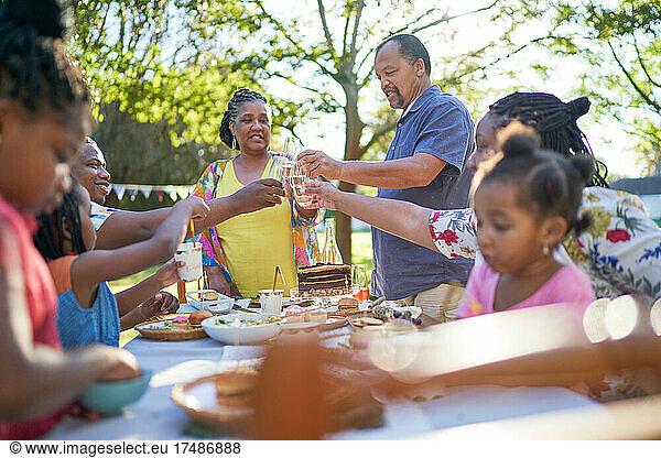 Multigenerational family celebrating birthday at summer patio table