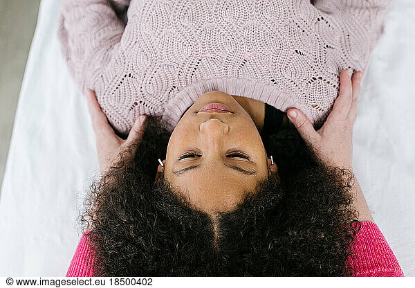 Multiracial Black girl getting craniosacral therapy inside clinic