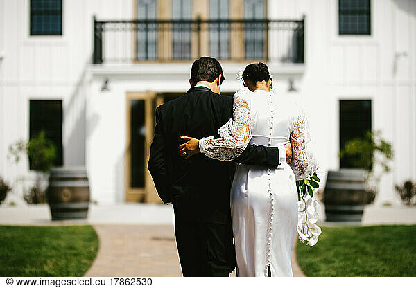 Multiracial bride and groom walk away after wedding
