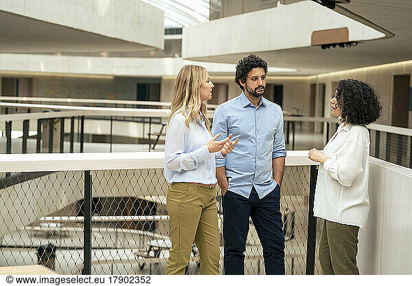 Multiracial business colleagues discussing ideas in corridor