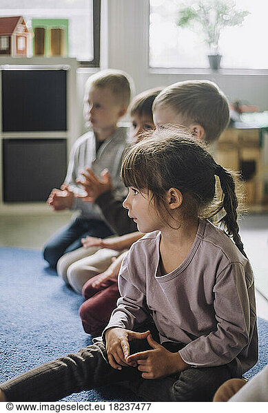 Multiracial children sitting on carpet in kindergarten