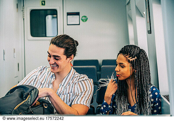 Multiracial couple in train with backpack