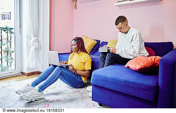 Multiracial couple of students preparing exams at home. Teamwork.