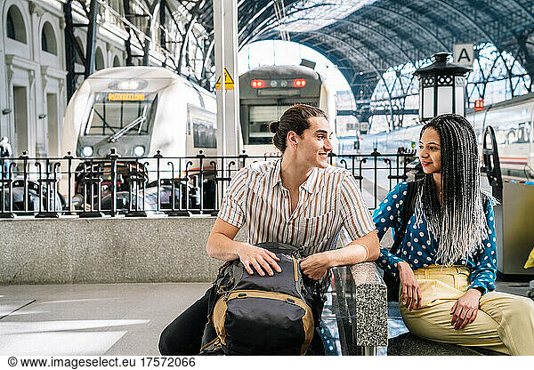 Multiracial couple sitting in railway station