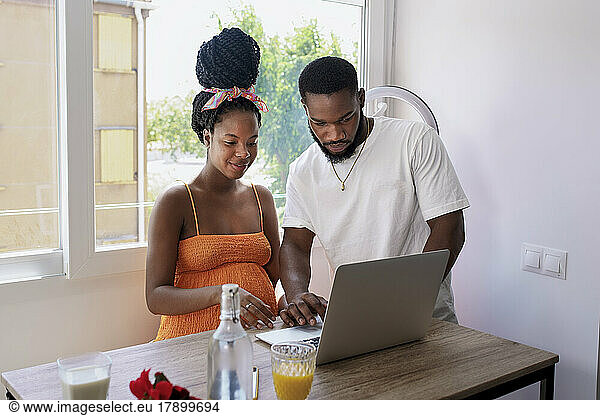 Multiracial couple using laptop on table at home