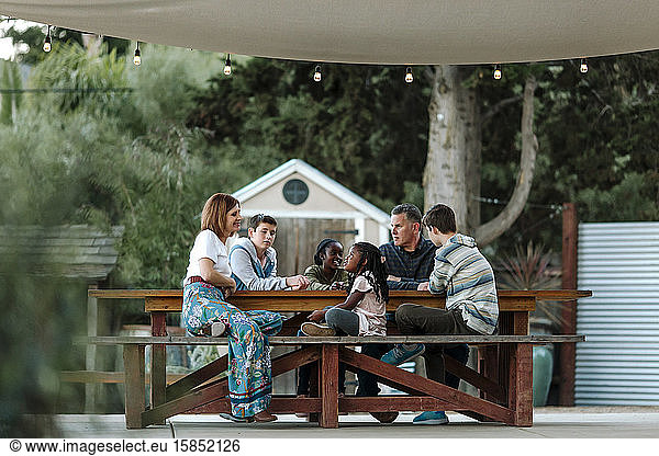 Multiracial family enjoying quiet time outdoors under sunshade