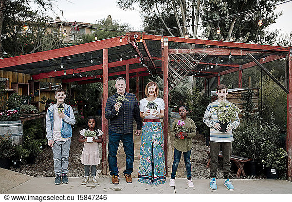 Multiracial family holding plants at nursery in California