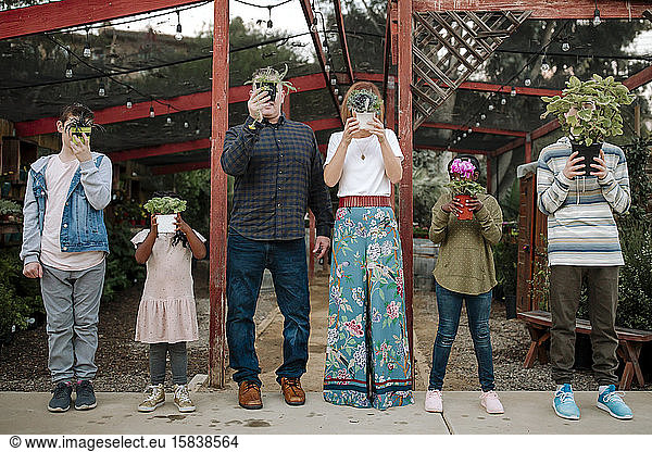 Multiracial family holding up plants at nursery in California
