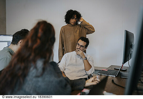 Multiracial female and male computer programmers discussing in startup company