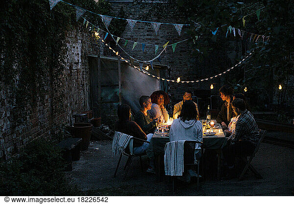 Multiracial friends during dinner party in illuminated back yard