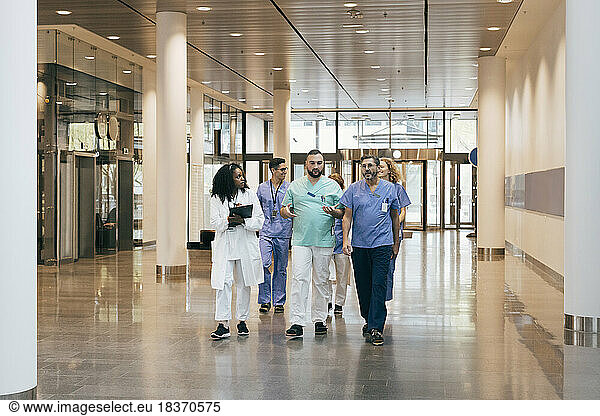Multiracial group of male and female hospital staff discussing while walking in lobby