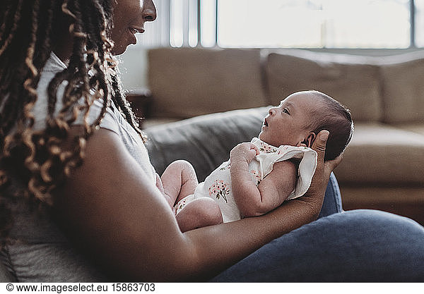 Multiracial infant held in the lap of ethnic mom with long braids