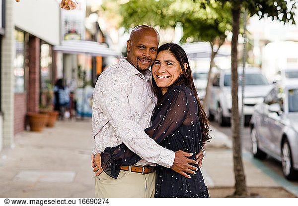 Multiracial Late Forties Couple Embracing on San Diego Sidewalk