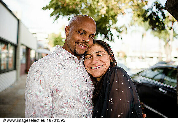 Multiracial Late Forties Couple Embracing on San Diego Sidewalk