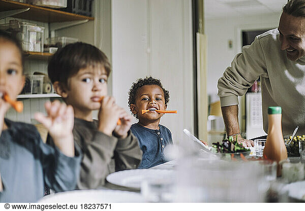 Multiracial male and female students eating carrots for breakfast in day care center