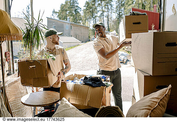 Multiracial movers unloading boxes from delivery truck