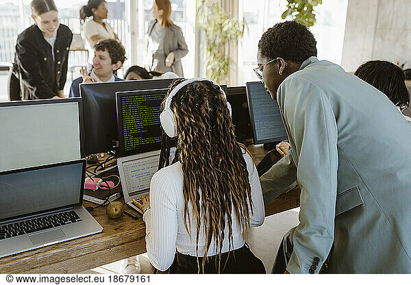 Multiracial programmers discussing over laptop at desk in office