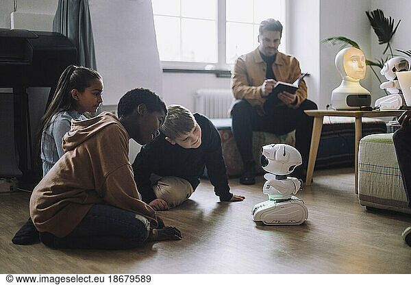 Multiracial students sitting in front of modern robot in innovation lab