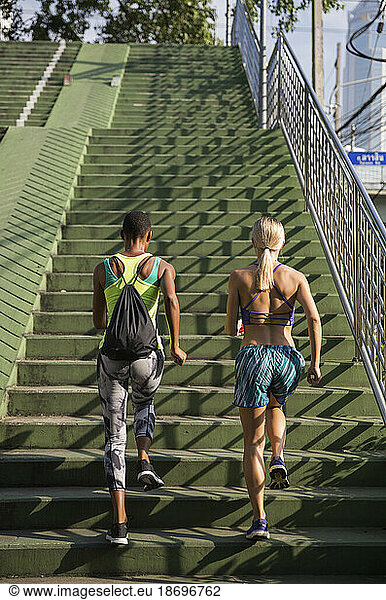 Multiracial women exercising on stairs at sunny day