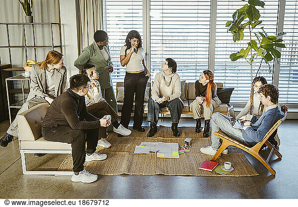 Multirassische männliche und weibliche Kollegen diskutieren während eines Treffens im Kreativbüro