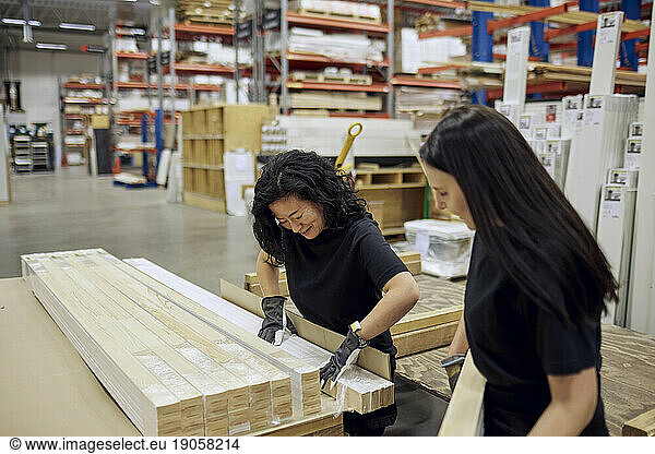 Multirassische weibliche Mitarbeiter ordnen Bretter in der Holzindustrie an