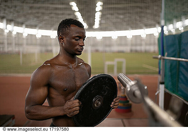 Muscular black athlete preparing barbell during workout