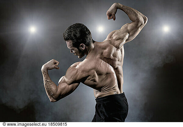 Muscular man flexing muscles while posing on stage