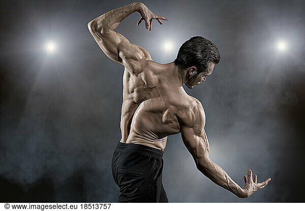 Muscular man flexing muscles while posing on stage