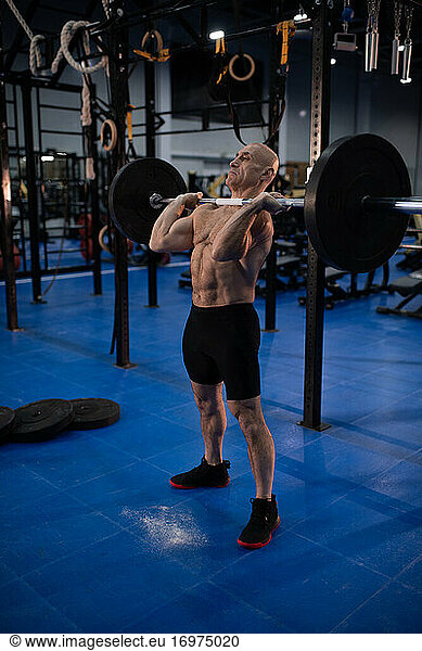 Muscular senior man with barbell in gym