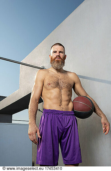 Muscular sportsman with basketball ball