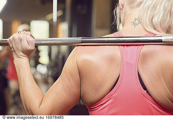 Muscular woman exercising with barbell