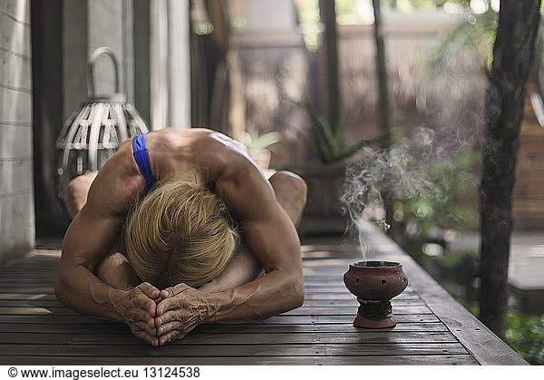 Muscular woman practicing yoga on porch