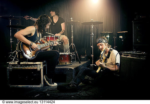 Musical band practicing in illuminated studio