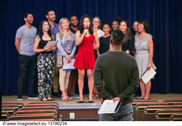 Musical conductor listening to choir on stage in language school
