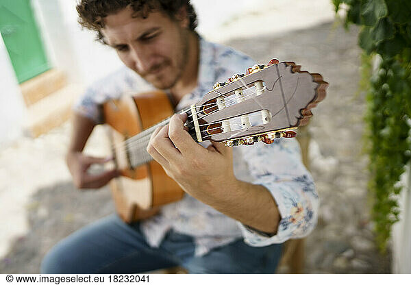 Musician playing Flamenco guitar sitting on chair