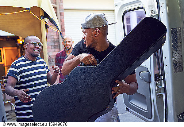 Musicians loading guitar case into van