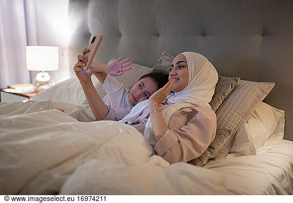 Muslim mother and daughter greeting father online