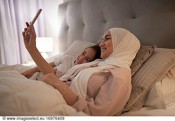 Muslim mother and daughter making video call at home