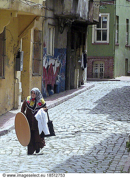 Muslim woman carrying a Table Top in Balat  Istanbul  Turkey
