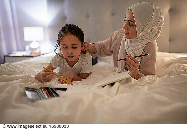 Muslimische Mutter kümmert sich um ihre zeichnende Tochter